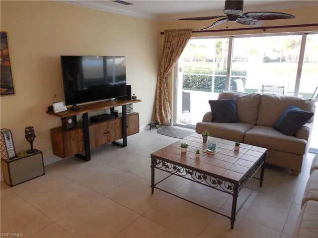 Living room featuring ceiling fan, ornamental molding, and light tile patterned floors