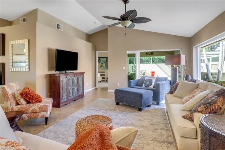 Living room featuring light tile patterned flooring, ceiling fan, and high vaulted ceiling