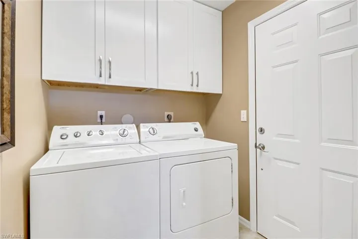 Washroom with washer and clothes dryer and cabinets