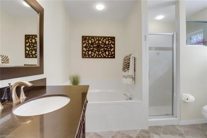 Full bathroom featuring toilet, vanity, plus walk in shower, and tile patterned flooring