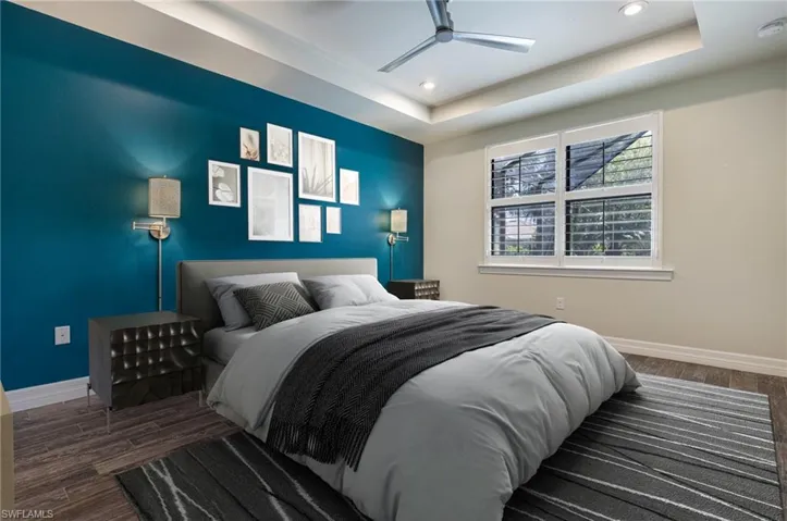 Bedroom featuring ceiling fan, a raised ceiling, and dark hardwood / wood-style floors