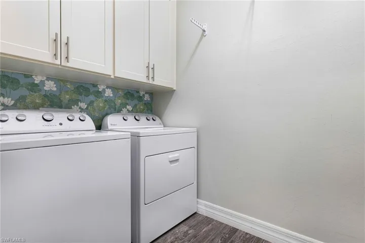 Clothes washing area featuring independent washer and dryer, dark hardwood / wood-style flooring, and cabinets