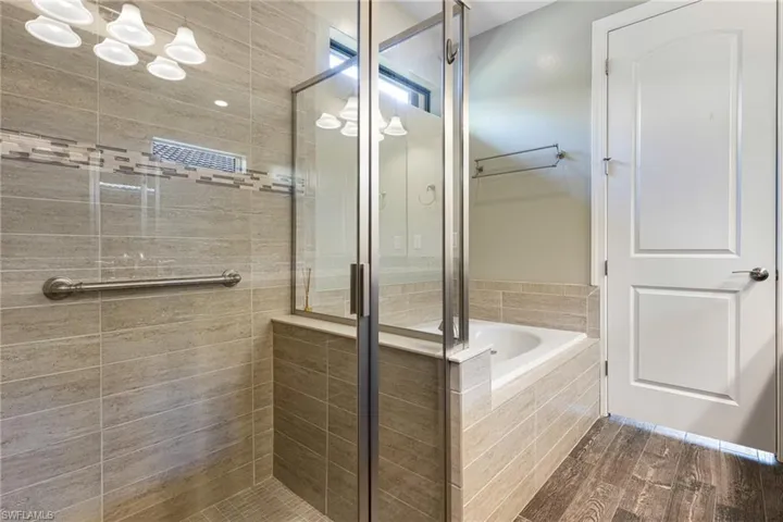 Bathroom featuring shower with separate bathtub and wood-type flooring