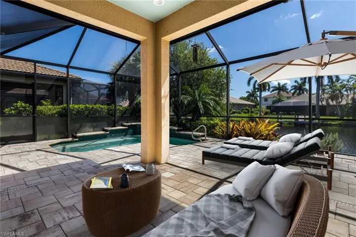 View of swimming pool featuring an outdoor hangout area, glass enclosure, and a patio