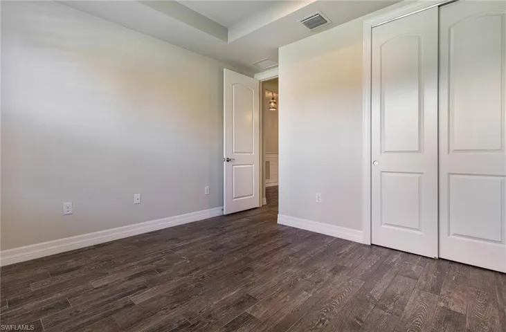 Unfurnished bedroom with dark hardwood / wood-style floors, a closet, and a tray ceiling