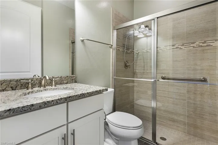 Bathroom featuring an enclosed shower, vanity, and toilet