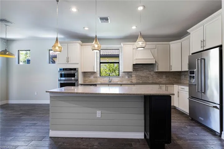 Kitchen with backsplash, stainless steel appliances, custom exhaust hood, and plenty of natural light