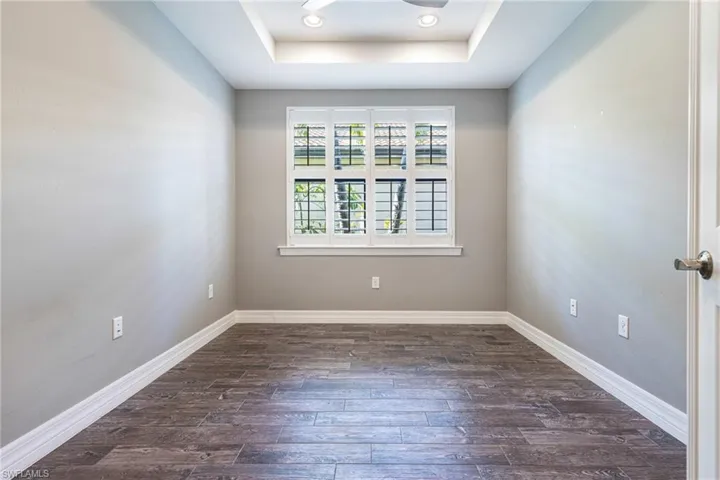 Spare room with dark hardwood / wood-style flooring and a tray ceiling