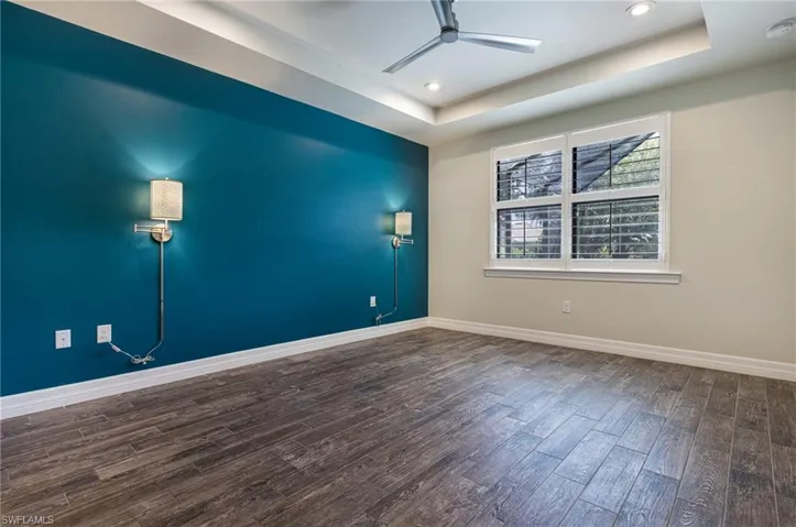 Spare room featuring ceiling fan, a raised ceiling, and wood-type flooring