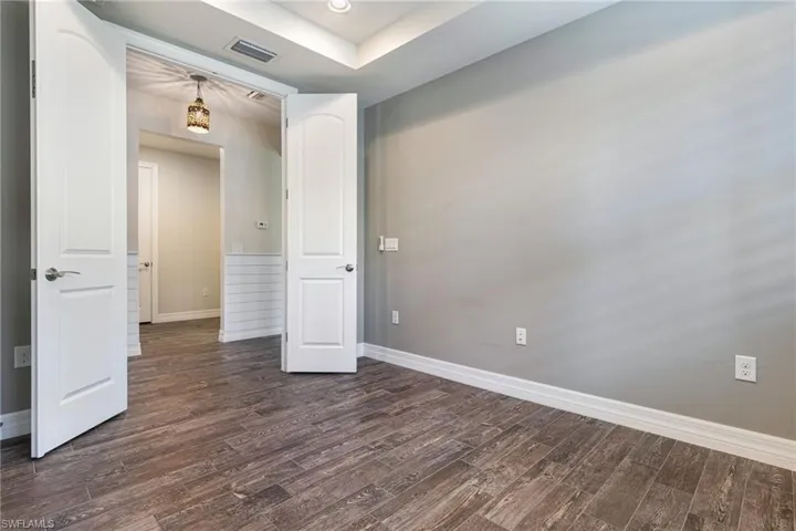 Unfurnished room featuring dark hardwood / wood-style flooring and a tray ceiling