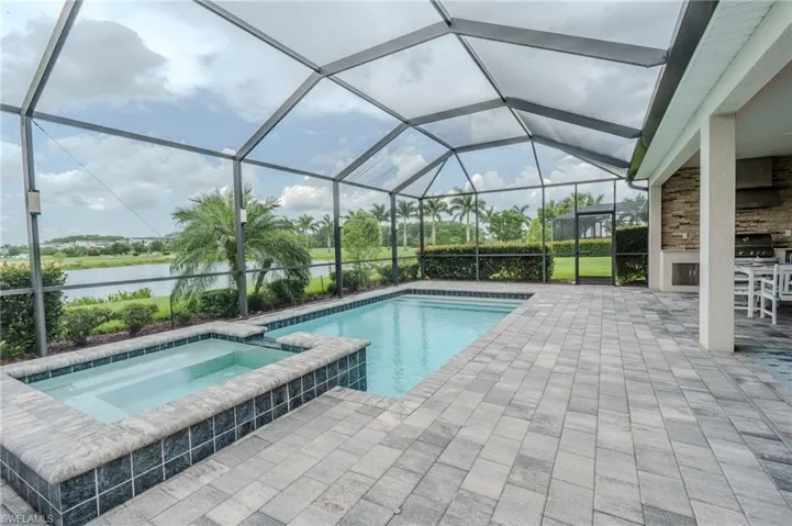 Screened outdoor living area featuring a rectangular pool and integrated spa