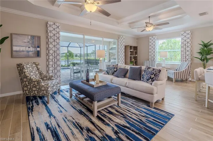 Living area featuring tray ceilings, ceiling fans, and wood-finish flooring