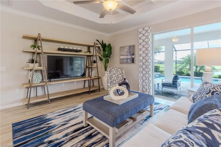 Living area with a tray ceiling, recessed lighting, and wood-finish flooring