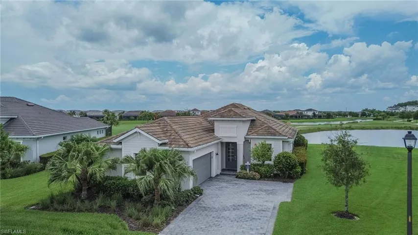 Single-story residence featuring a tile roof, light-toned siding, and a paver driveway