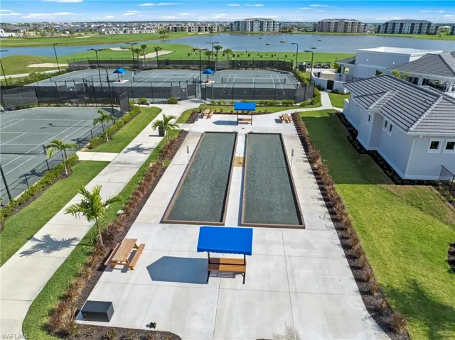 Recreational grounds featuring dual bocce ball courts with adjacent picnic areas, multiple tennis courts, and a surrounding paved walkway