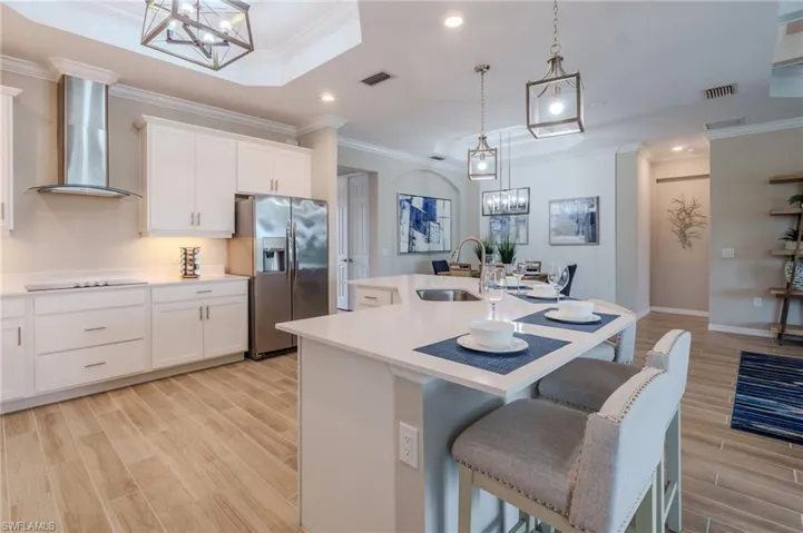 Spacious kitchen featuring white cabinetry, stainless steel appliances, light-toned countertops, and wood-finish flooring
