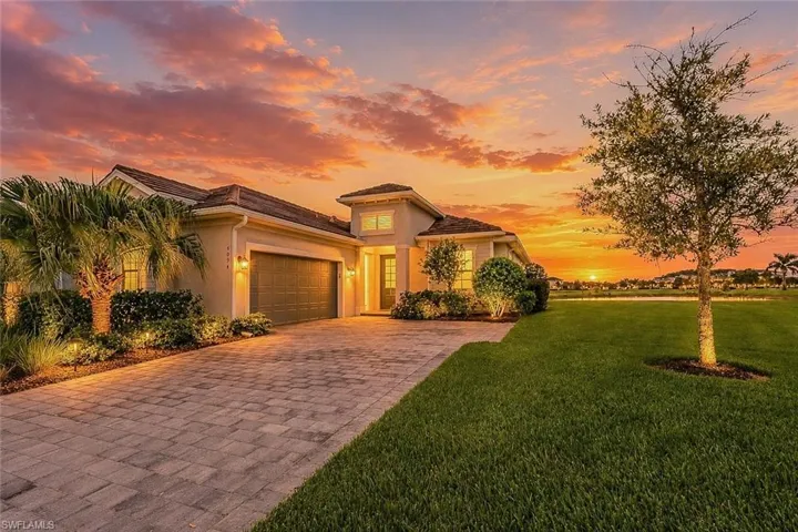 Contemporary stucco exterior featuring a two-car garage, paver driveway, and professional landscaping