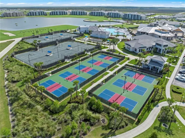 Multiple outdoor courts featuring various surface colors, surrounded by fencing and mature palm trees