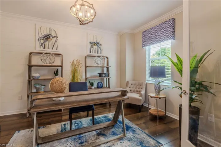 Interior room featuring a wood-finish floor, white crown molding, and a decorative ceiling light fixture