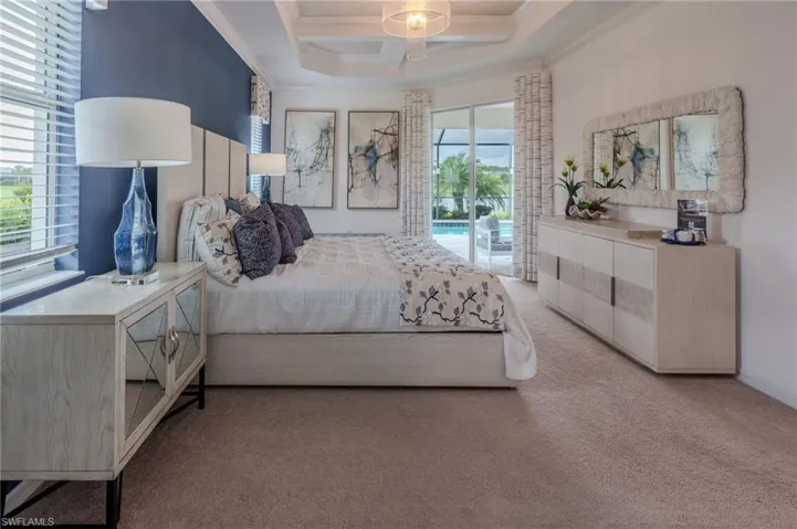 Bedroom featuring a tray ceiling with a central light fixture, carpet flooring, and a blue accent wall