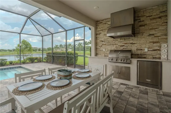 Screened lanai featuring a built-in outdoor kitchen with stainless steel appliances and stacked stone accent wall