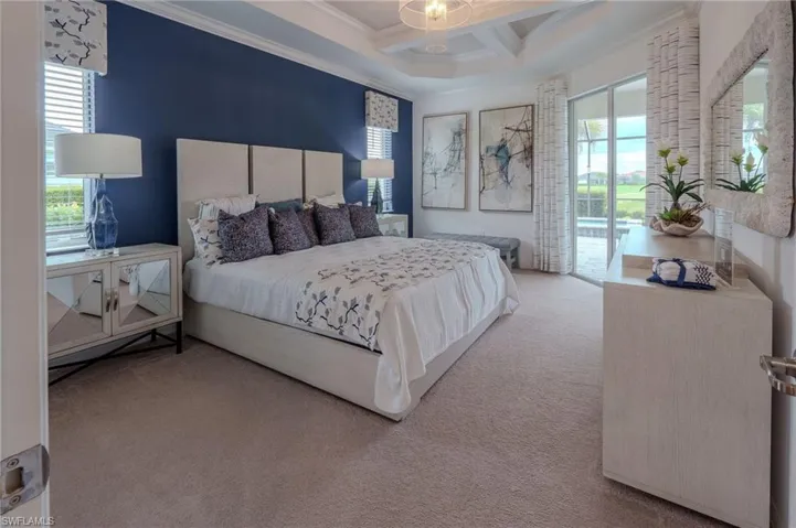Carpeted bedroom featuring a coffered ceiling, sliding glass doors to outdoor patio, and a deep blue accent wall