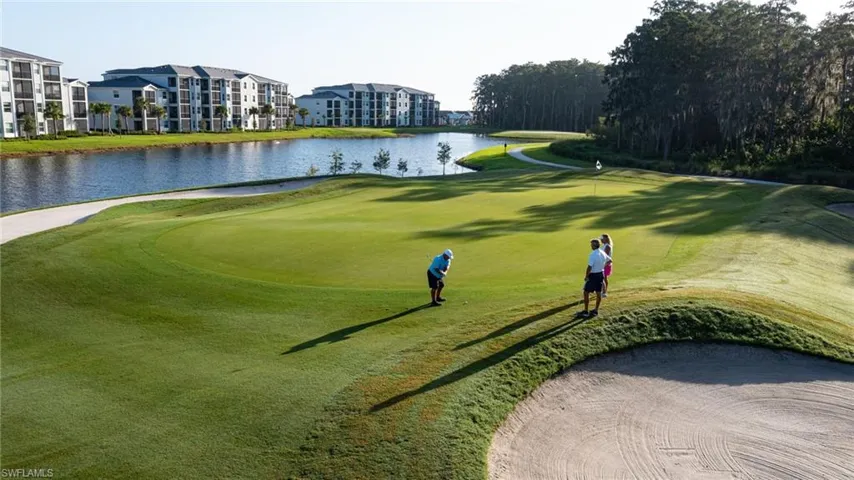 Expansive golf course green with sand trap, bordering a water feature