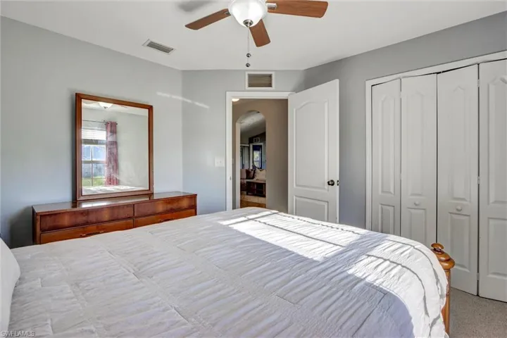Carpeted bedroom with ceiling fan, a closet, and arched walkways