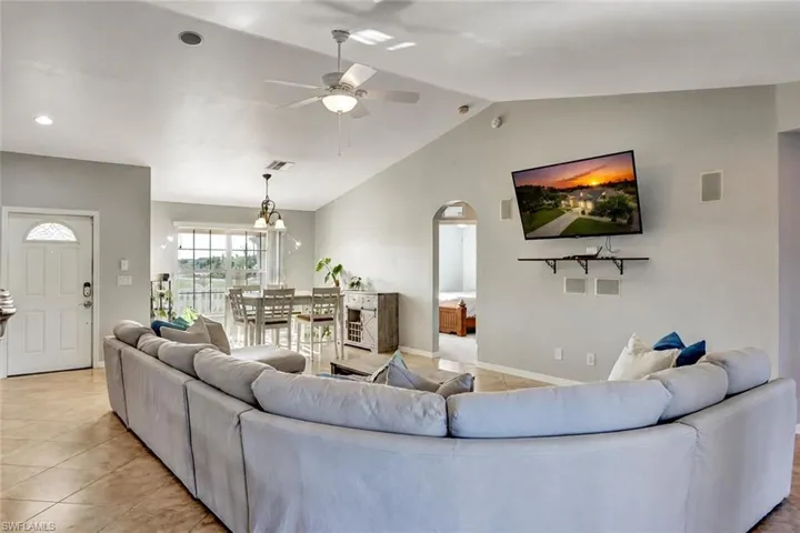 Spacious living area featuring vaulted ceilings, tile flooring, and integrated wall speakers