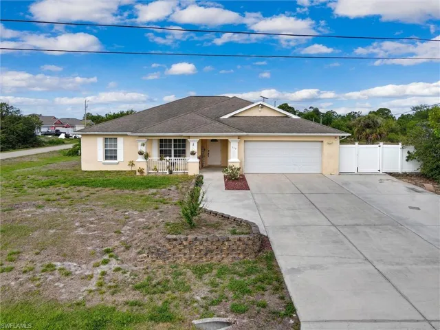 Ranch-style home featuring stucco siding, driveway, an attached garage, covered porch, and a gate