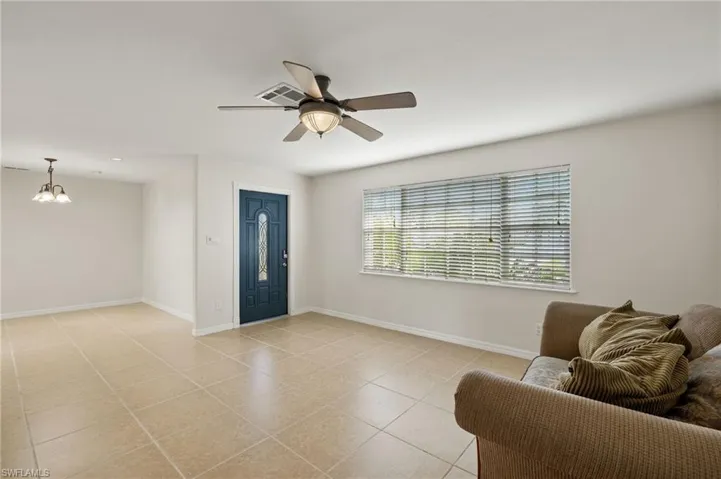 Tiled entryway with ceiling fan with notable chandelier