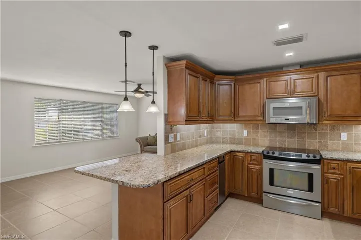 Kitchen with stainless steel appliances, pendant lighting, decorative backsplash