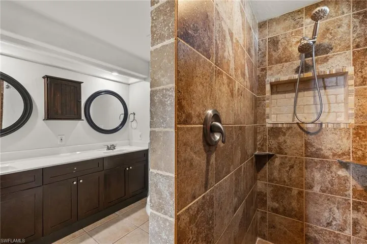 Bathroom featuring tile patterned flooring, a tile shower, and vanity