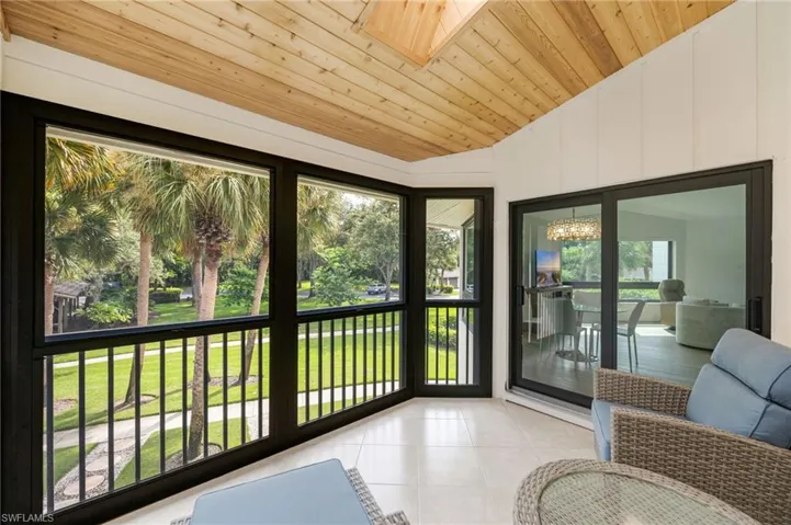 Screened lanai featuring a vaulted wood-finish ceiling, tile flooring, and multiple window panels