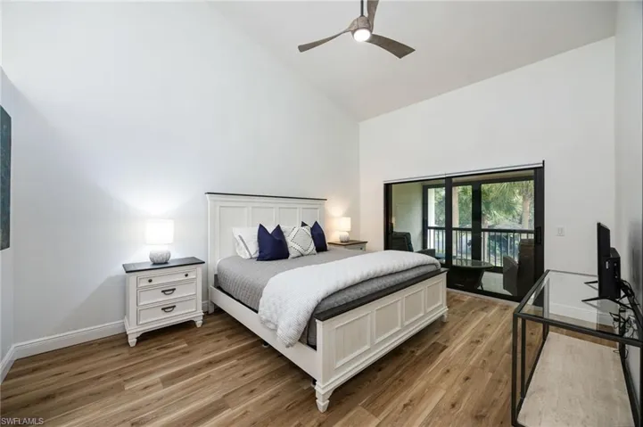 Vaulted ceiling, wood-finish flooring, sliding glass doors, ceiling fan, and balcony access