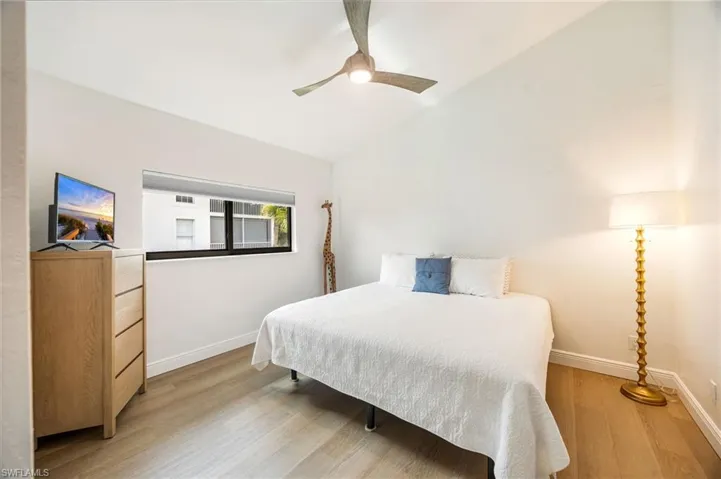 White walls with wood-finish flooring, a contemporary ceiling fan, and a transom window