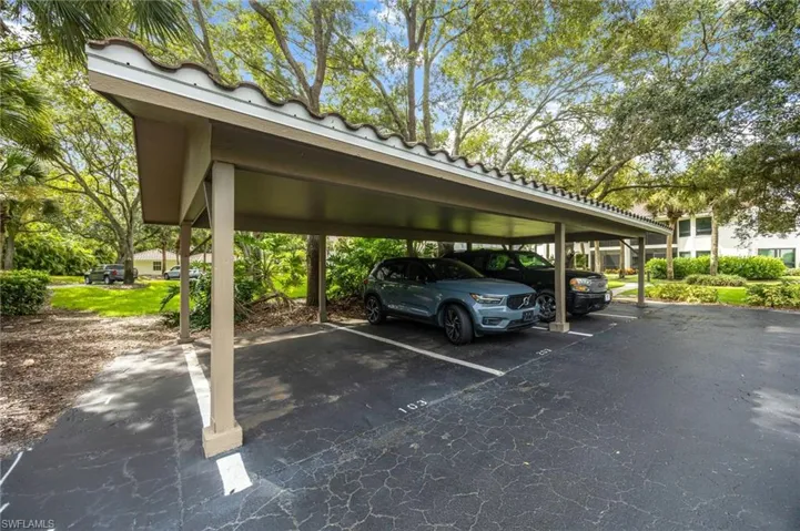 Carport structure featuring a tiled roof, supporting columns, and dedicated parking spaces