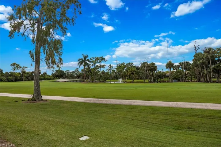 Expansive green space featuring a paved pathway and mature trees