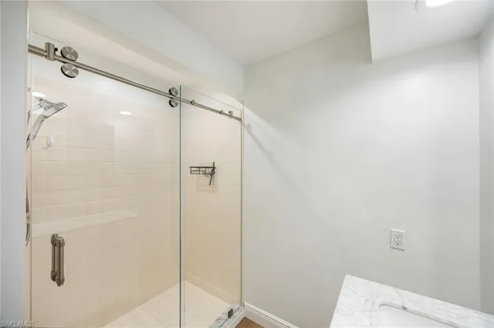 Glass-enclosed shower with a sliding barn door system, tiled walls, and a built-in shower bench