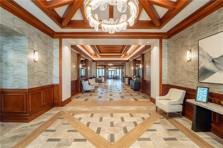 Tray ceiling with wood-finish beams, decorative chandelier, tile flooring with wood-finish accents, decorative wall sconces, and wainscoting