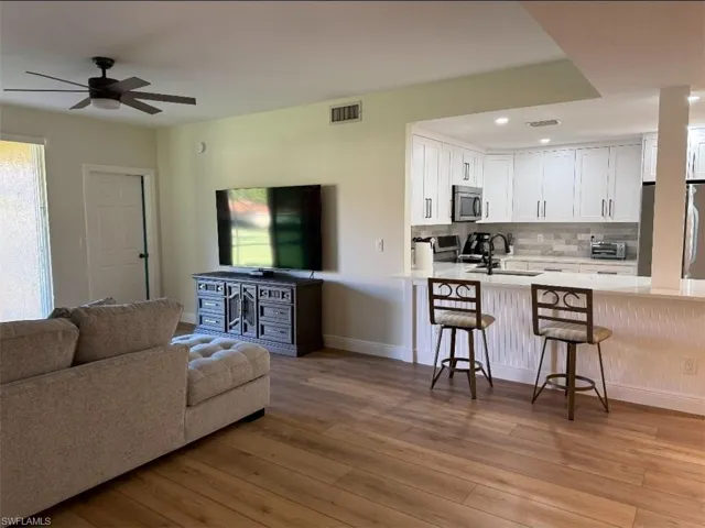 Living area with light wood-style floors, ceiling fan, and recessed lighting