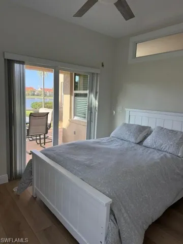 Bedroom with access to outside, dark wood finished floors, multiple windows, and a water view