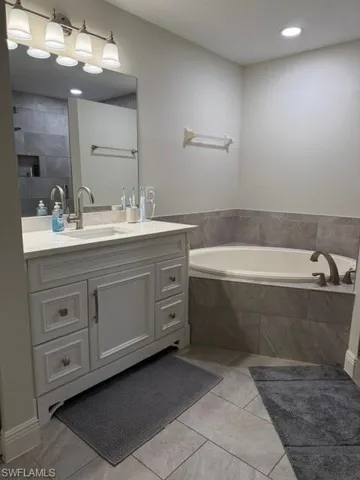 Bathroom featuring a garden tub, vanity, and light tile patterned flooring