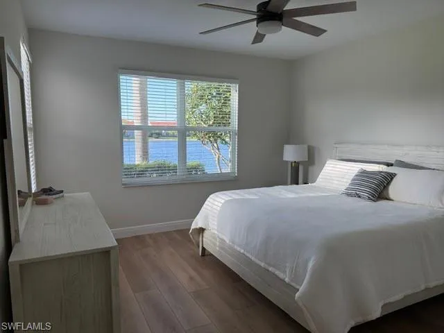 Bedroom featuring wood finished floors, a water view, and a ceiling fan