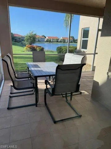 View of patio featuring a water view, a sunroom, and outdoor dining space