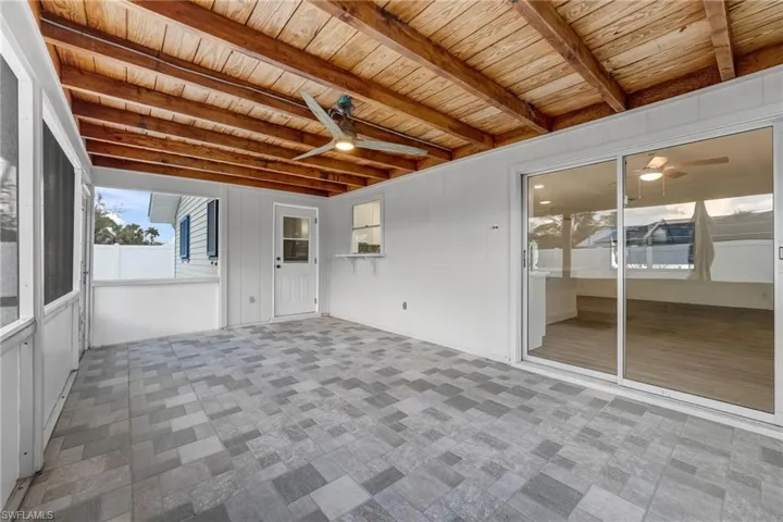 Inviting screened-in lanai with beautiful exposed wood beams, creating a warm and tastefully designed outdoor retreat.