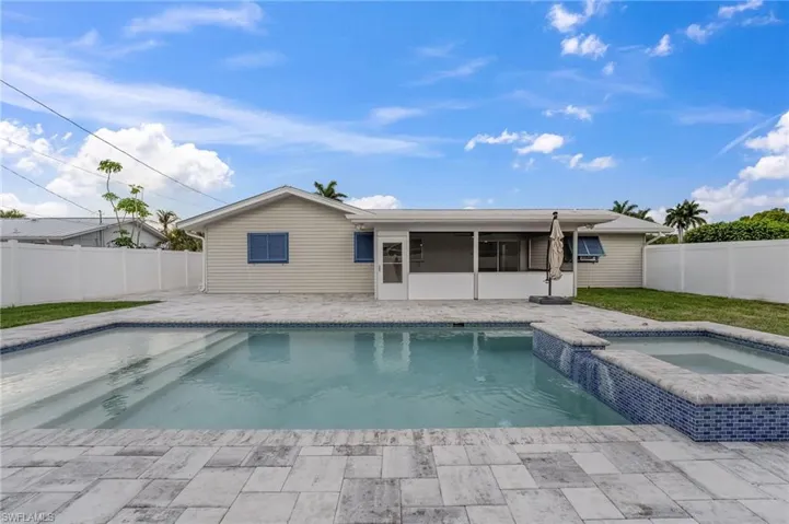 Beautiful pavered pool deck featuring a sparkling turquoise pool and spa, creating a spacious outdoor area ideal for entertaining.