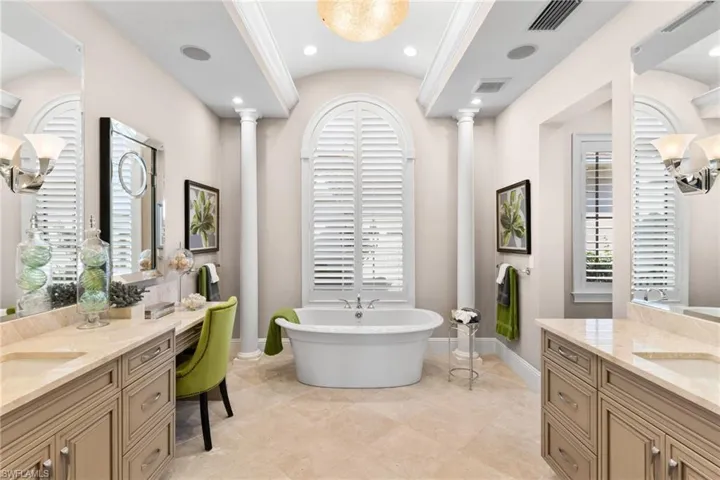Full bath featuring two vanities, a freestanding bath, a barrel ceiling, and recessed lighting