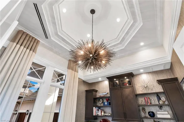 Detailed view of a chandelier, ornamental molding, and custom ceiling