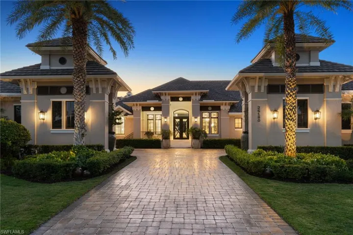 View of front facade featuring stucco siding, a lawn, decorative driveway, and french doors